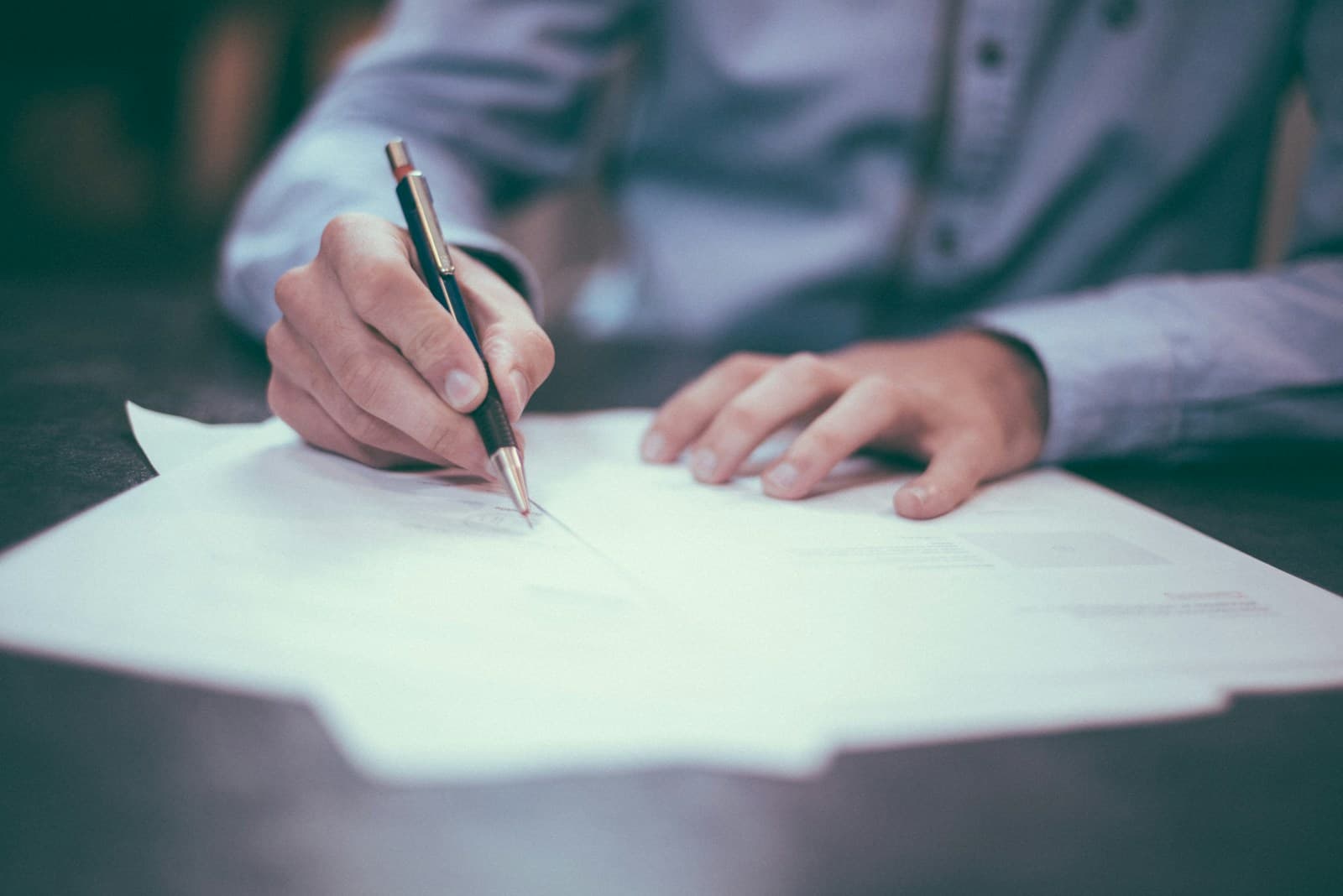 Close-up of professional paperwork, a pen and glasses on a desk